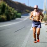 man jogging while listening using black earphones during day time