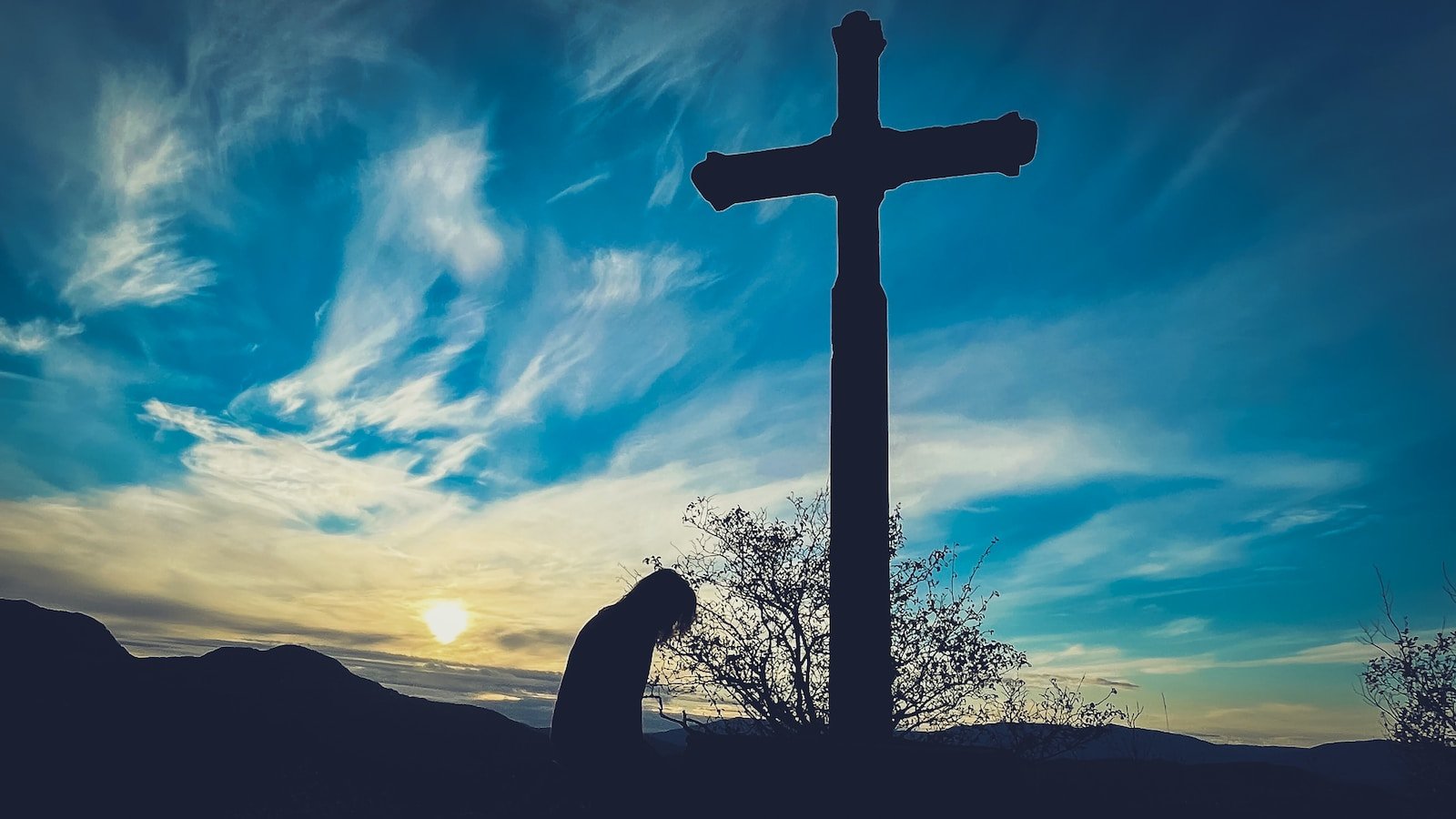 a person kneeling down in front of a cross. Forgiveness